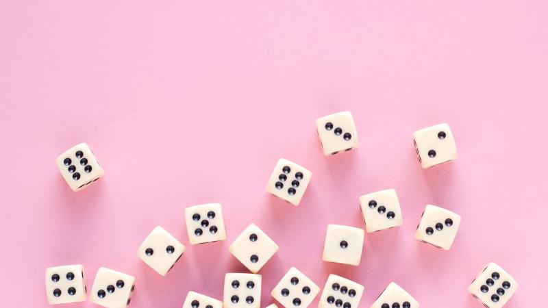 Pink background with a bunch of rolling dice